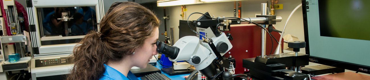 Une étudiante qui regarde dans un microscope