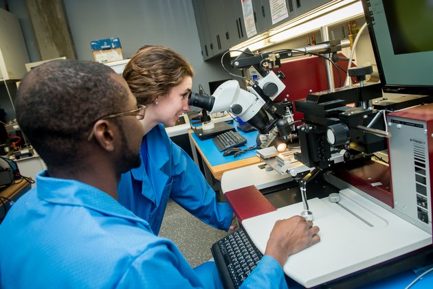 Deux personnes travaillant ensemble dans un laboratoire, et qui regardent dans un microscope