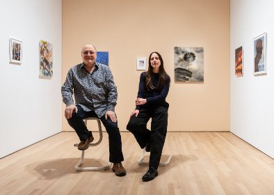 Un homme et une jeune femme posant sur des tabouret dans une galerie d'art