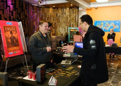 Un parrticipant de la Foire ludique de l'UdeS présentant son jeu de carte éducatif à un membre du public.