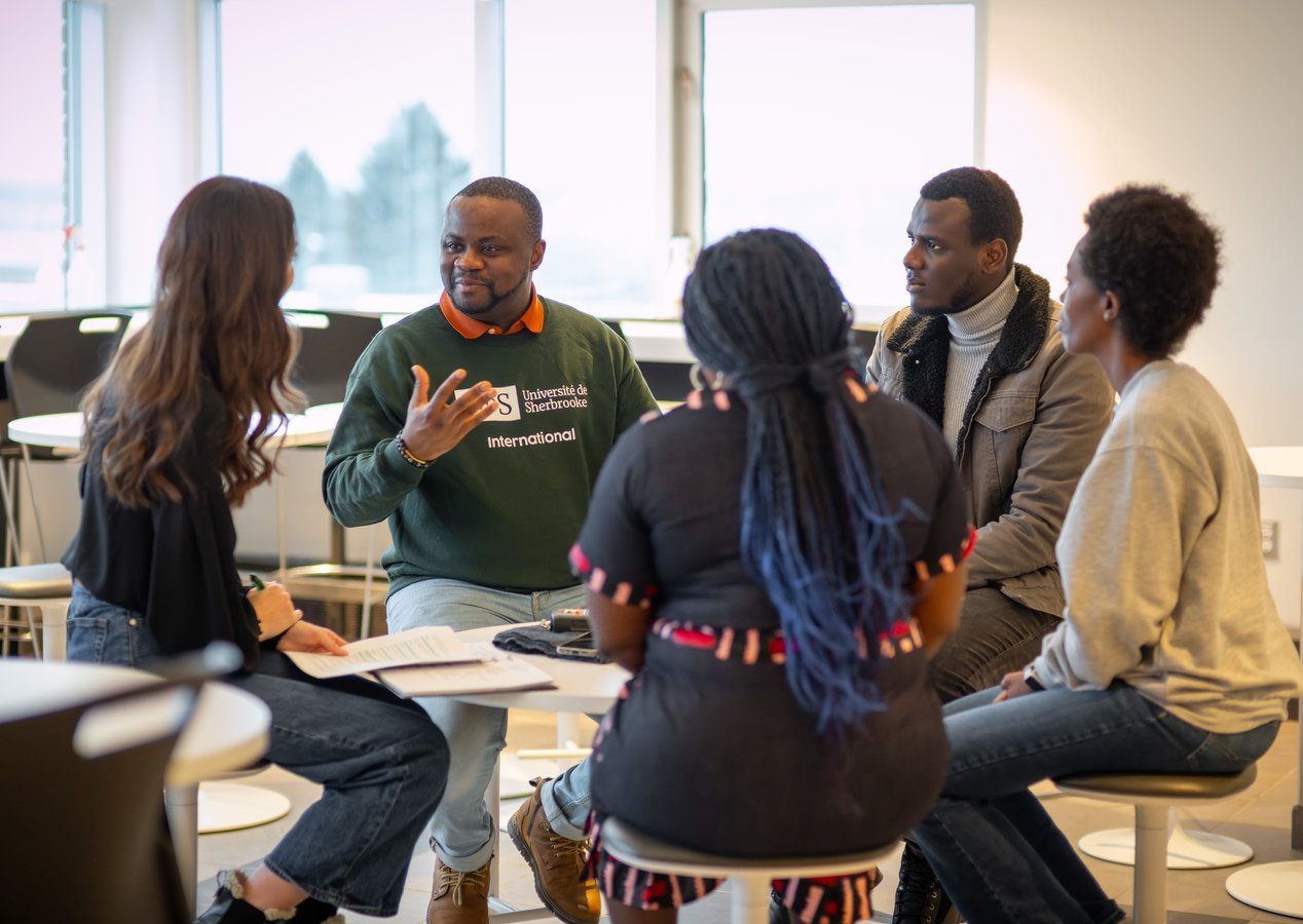 Les personnes étudiantes Brillele Verdie Jogo Guédia, Mahoro Nibaruta, Adama Bocoum, Ansadou Cherenfant et Laurie Gendron discutent autour d'une table.