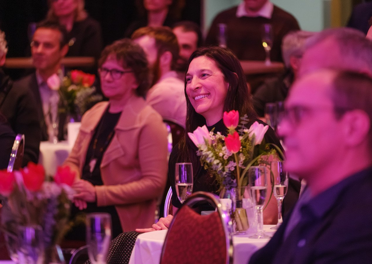 Femme souriante recevant des hommages lors d'une cérémonie de remise de prix.