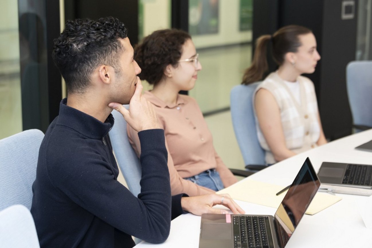 Un étudiant et deux étudiantes écoutent attentivement le partage d'expérience