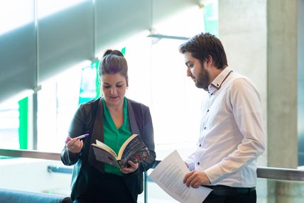 Une étudiante et un étudiant de la maitrise en littérature regarde des éléments à l'étude dans un livre de référence