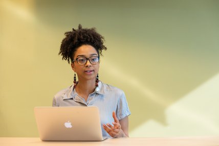 Une étudiante de maîtrise pose une questions, en classe, devant son ordinateur