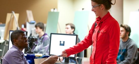 Une professeure aide un étudiant devant son ordinateur en classe