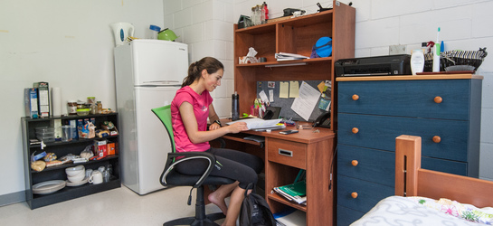 Une étudiante travaille à son bureau dans sa chambre de résidence