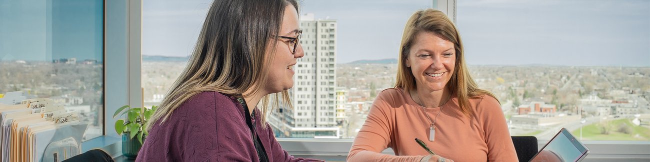 Deux femmes sont assises devant un ordinateur à une table