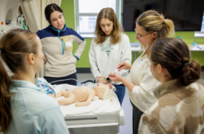 Instructrice avec des participants et un mannequin bébé qui pratique la réanimation