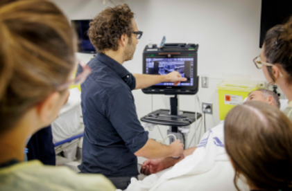 Instructeur qui montre l'écran de l'échographie qu'il fait sur le patient