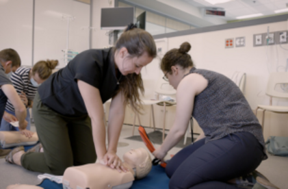 Deux participantes qui font la réanimation sur un jeune mannequin de réanimation