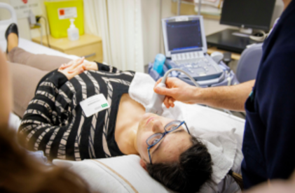 Patiente sur un lit d'hôpital avec un participant qui pratique l'échographie