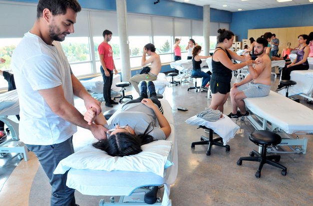 Des personnes étudiantes dans une classe de physiothérapie pratiquant certaines manipulations sur d’autres personnes étudiantes. 