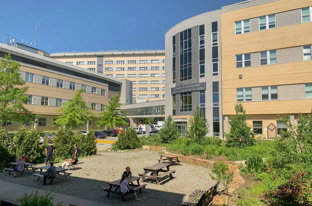Personnes qui discutent dans une aire de détente extérieure avec des tables de pique-nique.  