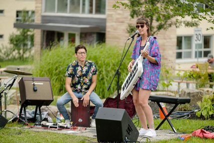 Un homme et une femme aux allures décontractées donnent un spectacle musical en plein air au Campus principal