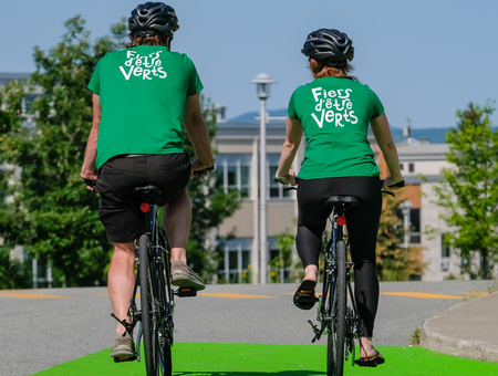Deux cyclistes de dos avec chandails verts portant inscription Fiers d'être verts.