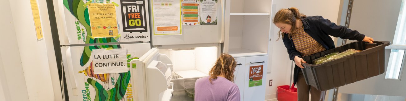 Étudiant et étudiante devant un frigo communautaire.