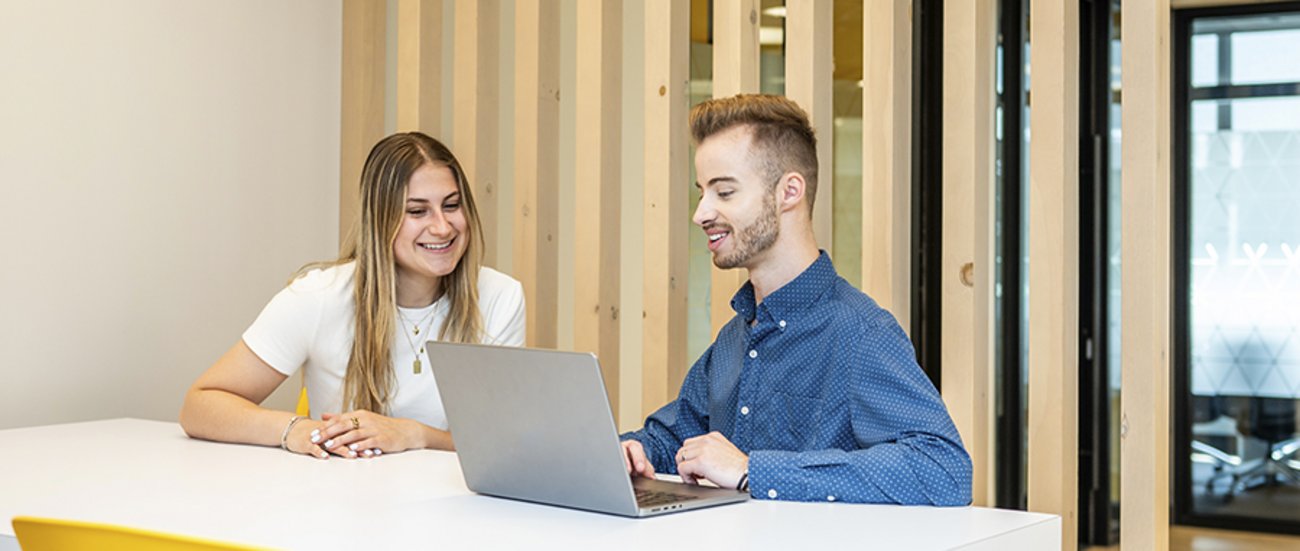 Une femme et un homme sont assis à une table de la Firme-école