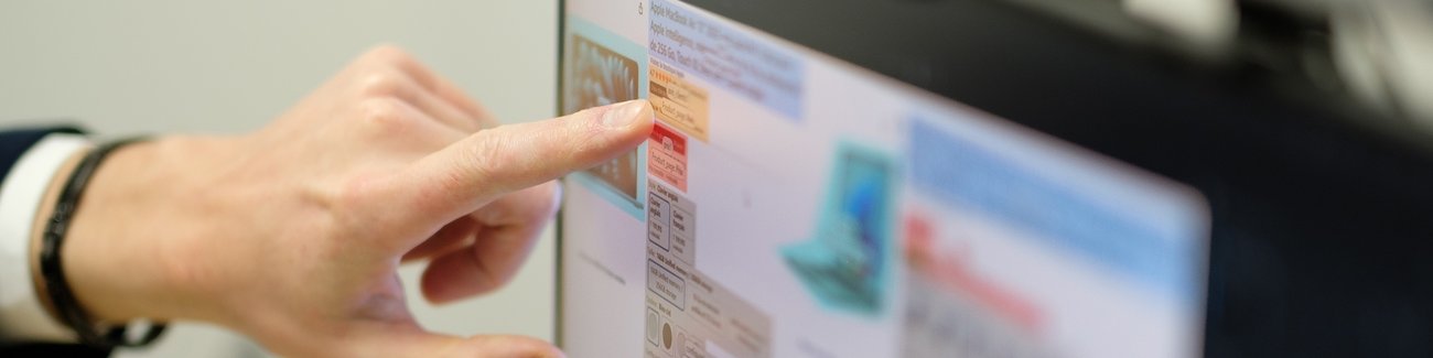 Une main pointe l'écran d'un ordinateur