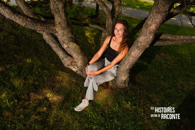 Emmy Ouellet assise au ceux d'un arbre, dans ses racines
