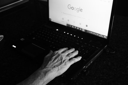 La main de Monique Létourneau est posée sur un clavier d'ordinateur portable, où s'affiche Google