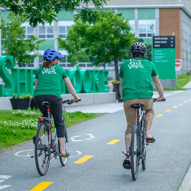 Deux personnes du Réseau Fiers d'être vert circulent à vélo sur le Campus principal