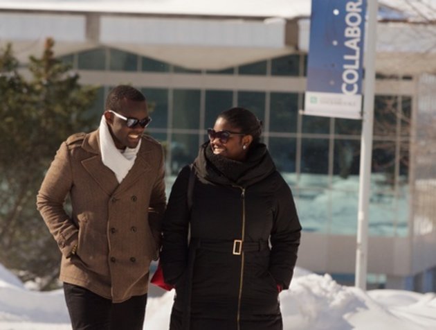 Deux étudiants internationaux marchent ensemble sur le campus enneigé.