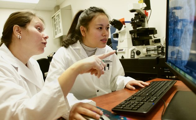 Deux étudiantes en laboratoire discutent devant un écran d'ordinateur