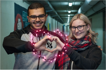 Photo de deux étudiants internatioinaux qui forment conjointement un coeur avec leurs mains.
