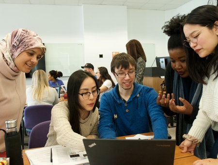 Plusieurs étudiants de différentes cultures sont rassemblés autour d'un ordinateur.