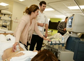 Une intervenante de la santé montre à un étudiant comment pratiquer un examen ultrasons sur un patient