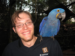 Junior et un norme perroquet ara perch sur son paule, au parc des oiseaux de Foz do Iguau.