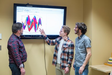  Deux étudiants qui montrent à leur professeur un graphique sur un écran