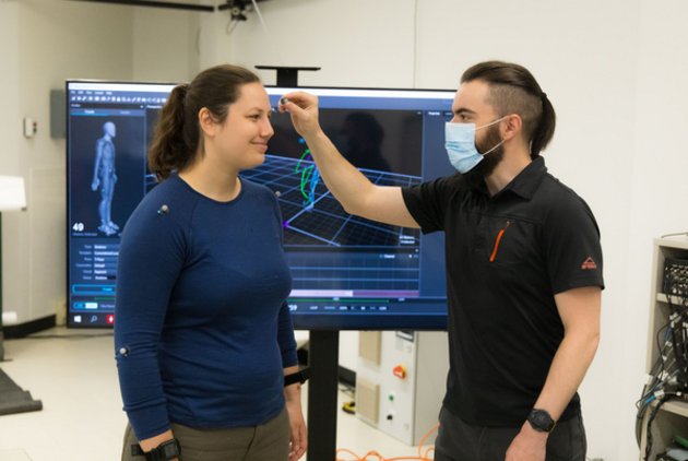 Un technicien qui pose un capteur sur la tempe d'une femme.