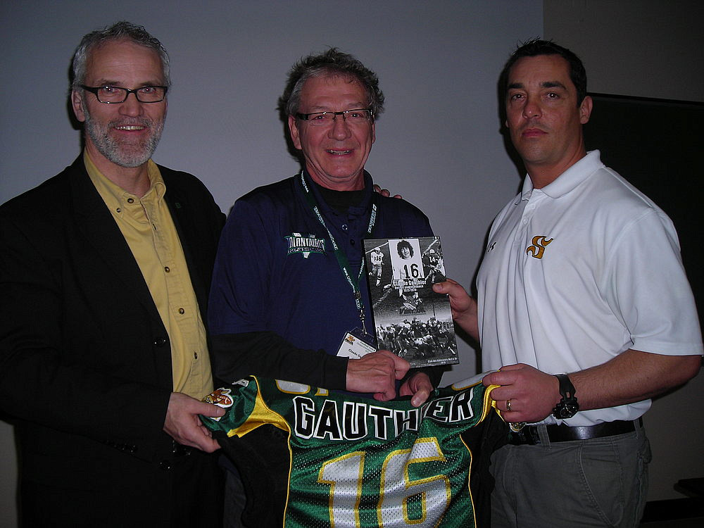 Alain Lapointe, dg du programme de football Vert&nbsp;&&nbsp;Or, et Andr&eacute; Bolduc, entra&icirc;neur-chef de l'&eacute;quipe, ont remis un chandail et une plaque &agrave; Claude Gauthier pour souligner sa contribution &agrave; titre de b&acirc;tisseur du football estrien.
