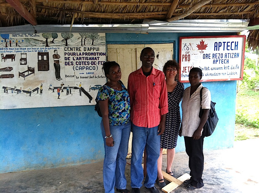 Deux étudiantes de l'Université publique du Sud-Est à Jacmel, Nadine Saint-Germain et Louisena Gontrand, et le directeur de l'École professionnelle de Jacmel, Christian Duplan, dans l'un des ateliers du réseau coopératif APTECH à La Biche.
