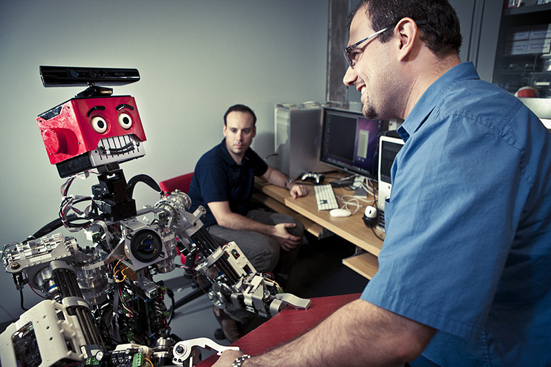 Le professeur Waël Suleiman du Département de génie électrique et de génie informatique interagissant avec un robot.
