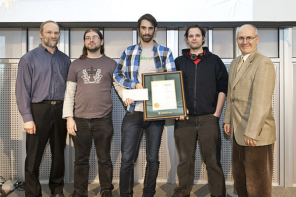 Alexei Nordell-Malkovits, Keven Marin et Alexandre L&eacute;tourneau, repr&eacute;sentants du groupe Hackus, re&ccedil;oivent le prix des mains de Martin Buteau, vice-recteur aux ressources humaines et &agrave; la vie &eacute;tudiante, et du professeur Gabriel Girard, directeur du D&eacute;partement d'informatique.