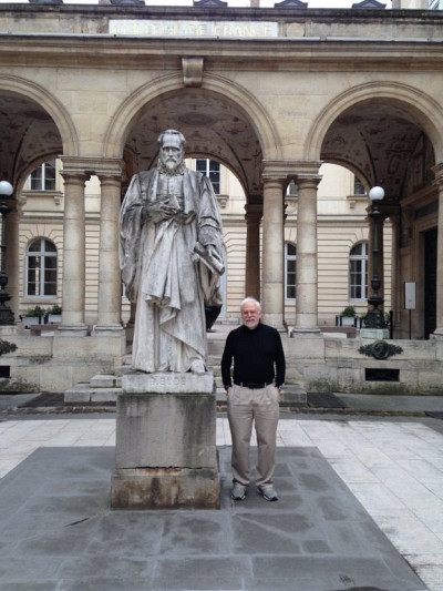 Le Pr André-Marie Tremblay dans la cour du Collège de France, à côté de la statue de Guillaume Budé, sous les conseils duquel François premier a fondé l'institution.
