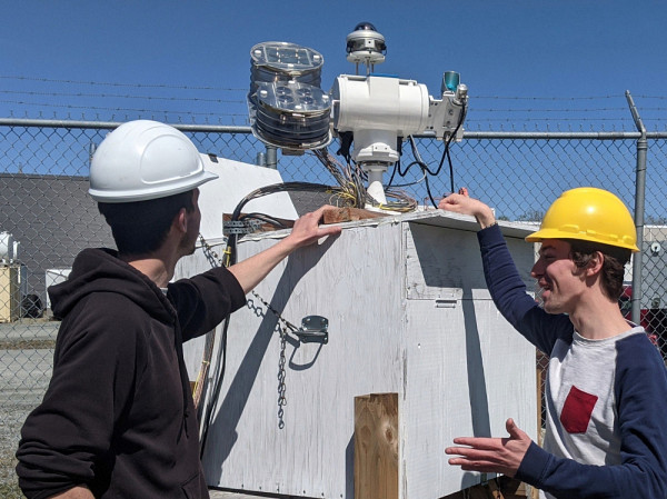 Mathieu Blanchard qui aide Mathias de Schietere, un stagiaire de son groupe de recherche, sur une des plateformes d’instrumentation dans le parc solaire de l'UdeS derrière le 3IT.