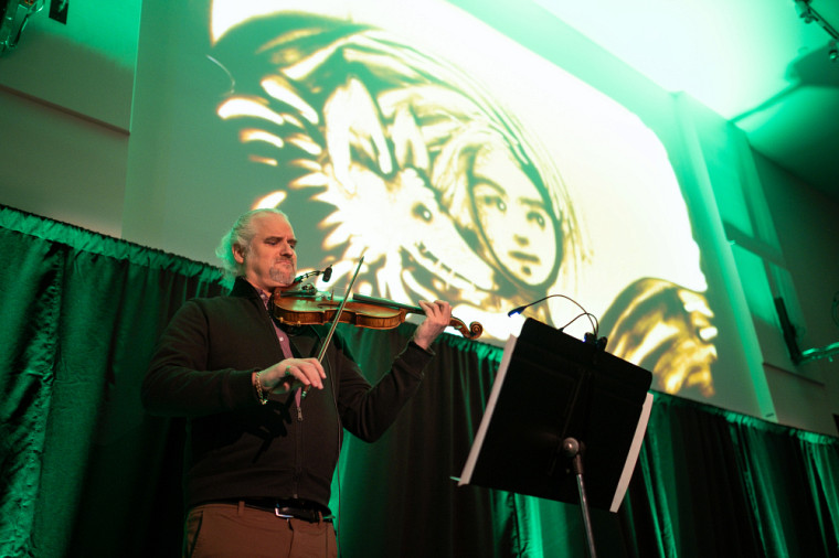 Violinist Charles Van Goidtsenhoven's music accompanies artist Josée Courtemanche, also a professional at UdeS, in the creation of drawings in sand projected on a screen during the Strategy launch event.