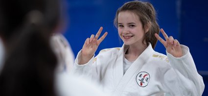 Une adolescente en judo gui sourit à l'objectif.