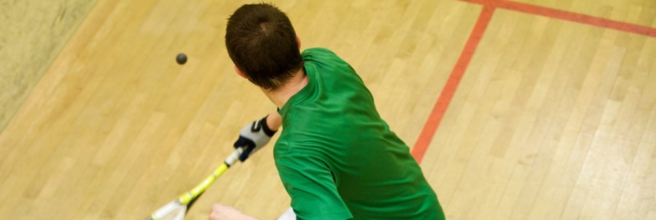 Un garçon joue au squash.