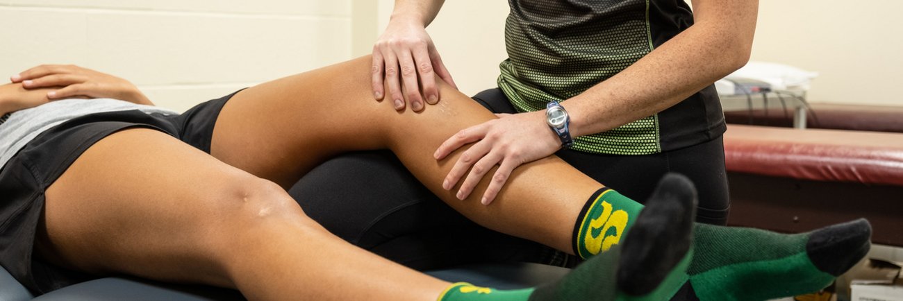 Une patiente se fait traiter la jambe par une physiothérapeute.