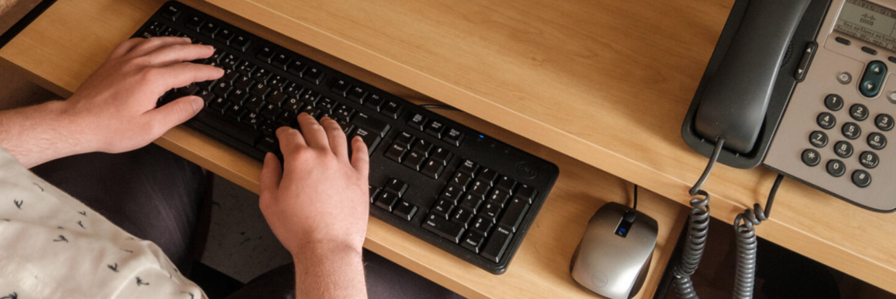 Des mains saisissent du texte à un clavier d'ordinateur.